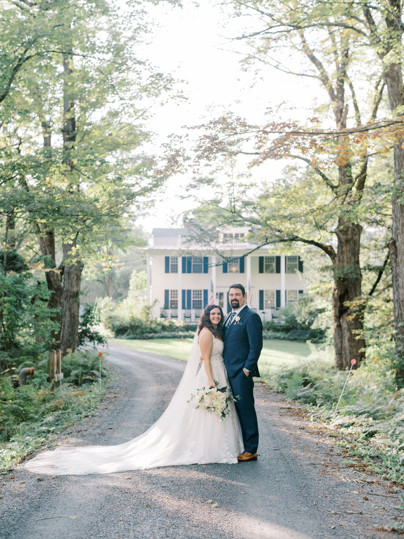 Burlington Vermont wedding florist with white wedding flowers at a southern vermont wedding venue white and green secret garden farmhouse romantic wedding bride holding a white and green bridal bouquet and groom with a boutonnière