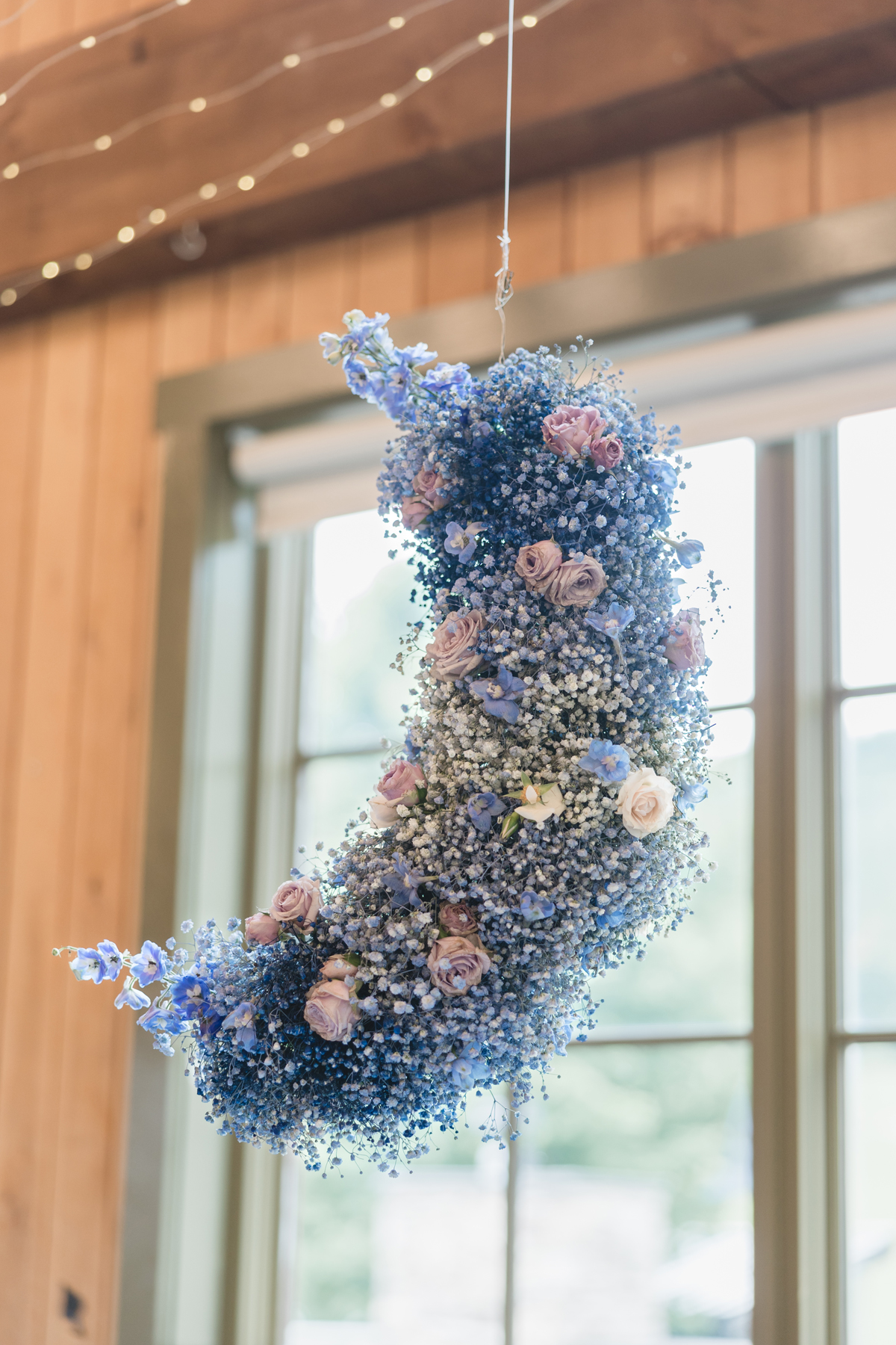 Burlington Vermont wedding florist Taylor Swift Lover album themed wedding. Pastel color palette at Sugarbush Vermont wedding venue reception sweetheart table flowers and a babys breath moon shaped ceiling chandelier floral installation
