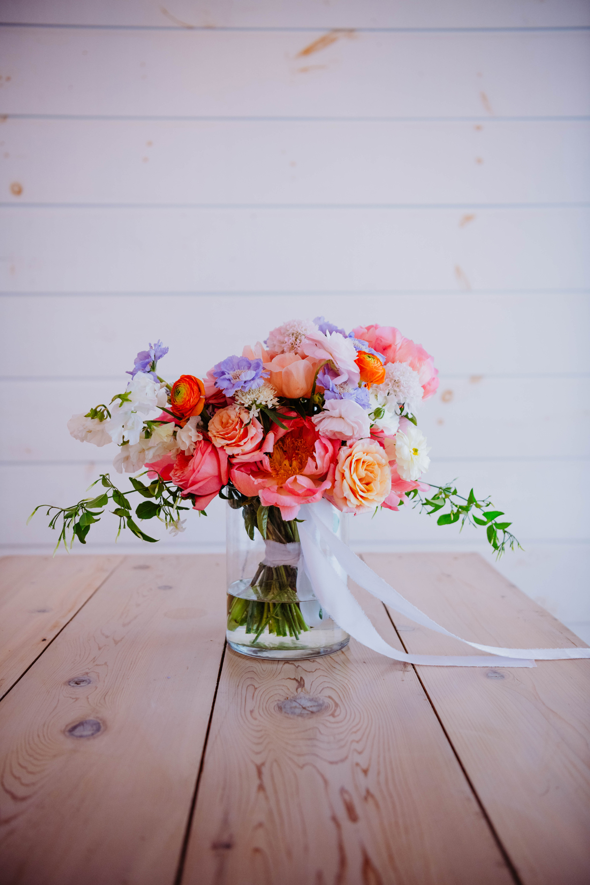 Stowe VT mountain view romantic wedding florals wedding pink and citrus wedding bridal bouquet flowers and bride and groom after the ceremony by a Burlington Vermont Wedding Florist at the Barn at Smugglers Notch wedding venue