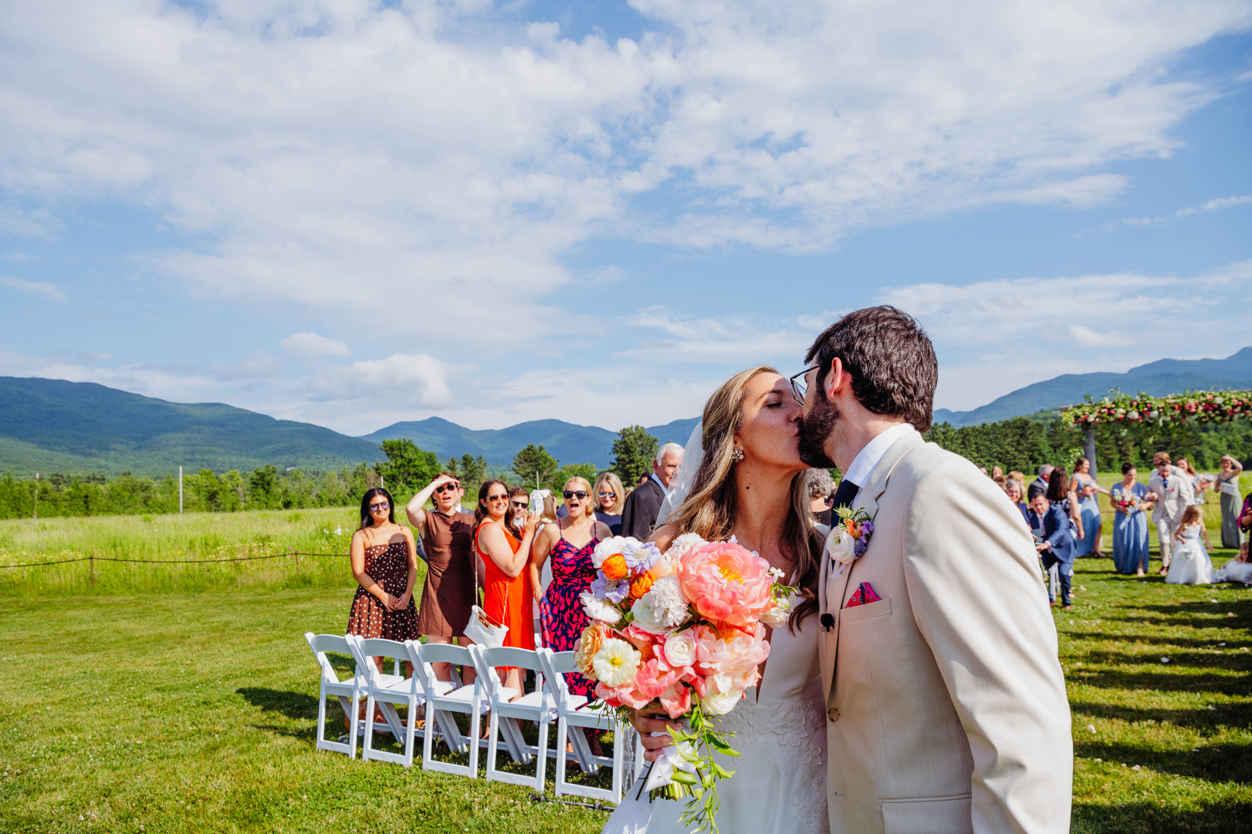 Stowe VT mountain view romantic wedding florals wedding pink and citrus wedding arch flowers and bride and groom after the ceremony by a Burlington Vermont Wedding Florist at the Barn at Smugglers Notch wedding venue