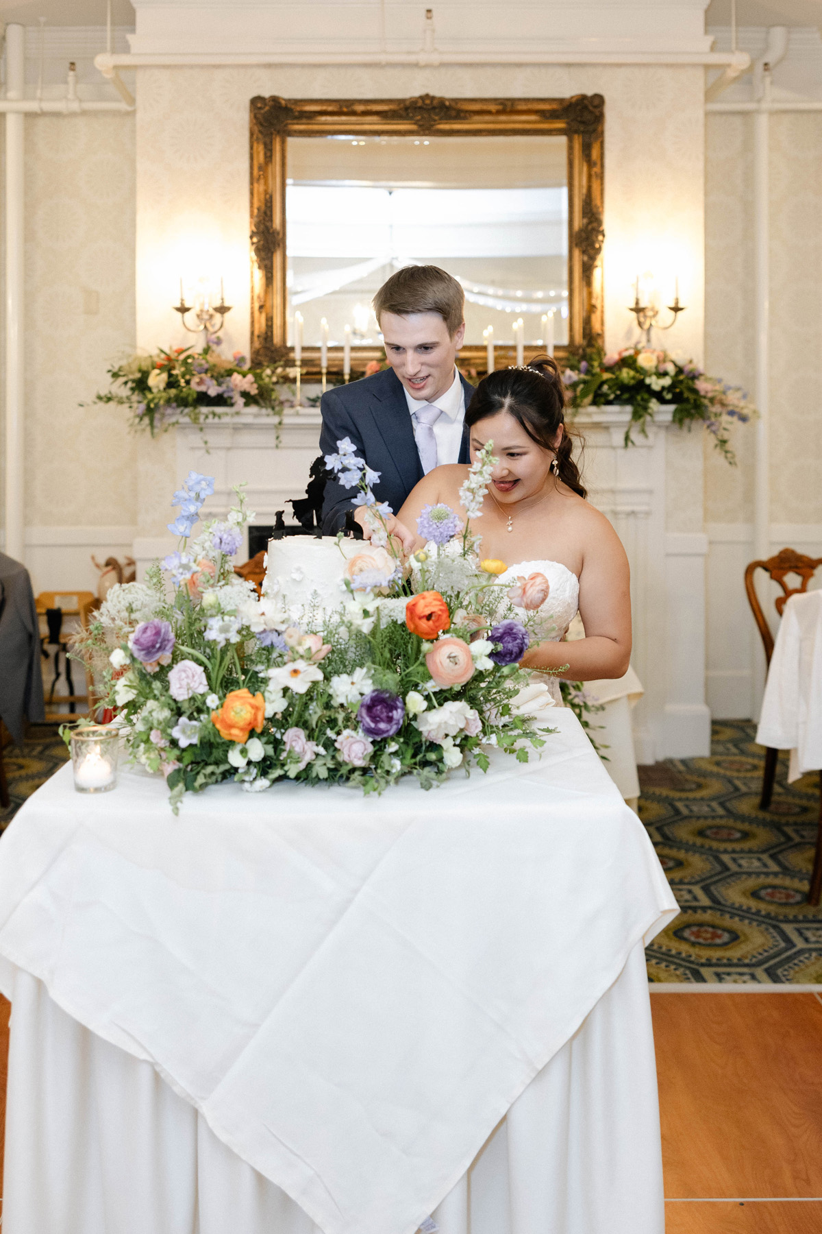 Burlington Vermont Wedding florist creating a bright citrus bridal bouquet with a couple and a cake meadow of flowers at a southern vermont wedding venue.